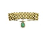 a close up of a bracelet with a green stone on it