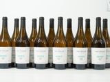 six bouteilles de vin sont alignées sur une surface blanche