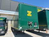 two semi trucks parked next to each other in front of a building