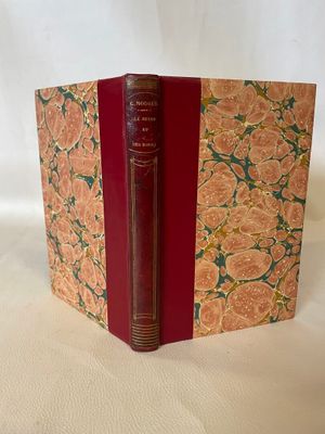 an old book with a red cover sitting on top of a white table