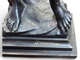 a bronze statue of a person with their feet on a book