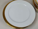 a stack of plates with gold rims on a table