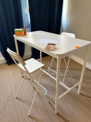 une table blanche avec deux chaises et un livre posé dessus