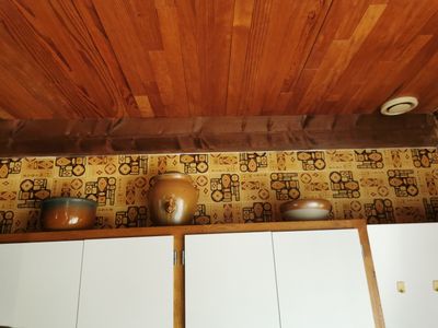 une cuisine avec un plafond en bois et un mur tapissé