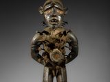 une statue en bois représentant un homme tenant une fleur