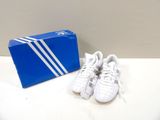 a pair of white shoes sitting next to a blue box