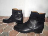pair of black leather ankle boots with buckles on a brick floor