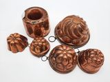 une image représentant un ensemble d'objets en cuivre posés sur une surface blanche