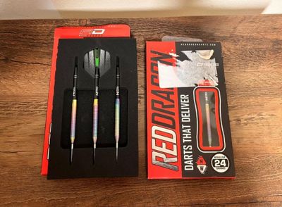 two darts and a dart in a box on a wooden table