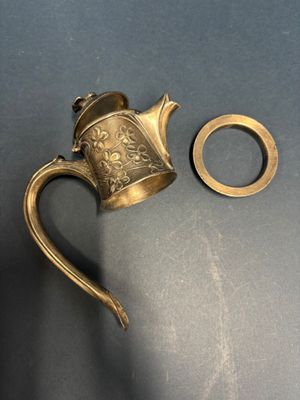 a brass teapot and a brass ring on a table