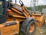 a backhoe of a tractor that is parked in the grass