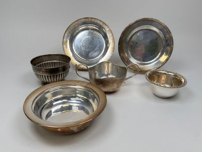 Des assiettes et des bols plaqués argent sont disposés sur une surface blanche