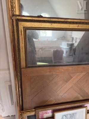 un grand miroir posé sur une table, à côté d'un cadre photo
