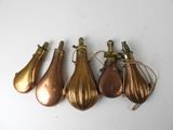 four antique brass tear shaped ornaments on a white surface