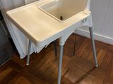 a white high chair with a sink in the middle of the room