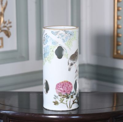 un vase orné d'un oiseau et de fleurs, posé sur une table