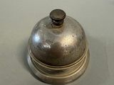 a silver bell sitting on top of a white table