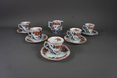 six tasses et soucoupes ornées de fleurs orange, posées sur une table