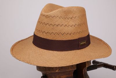 un chapeau marron posé sur une chaise en bois