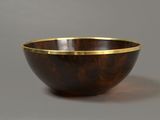 a wooden bowl with a gold rim sits on a gray surface