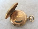 a gold pocket watch sitting on a white surface