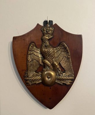 un bouclier en bois orné de deux oiseaux et surmonté d'une couronne