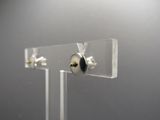 présentoir en acrylique transparent sur lequel est posée une paire de boucles d'oreilles
