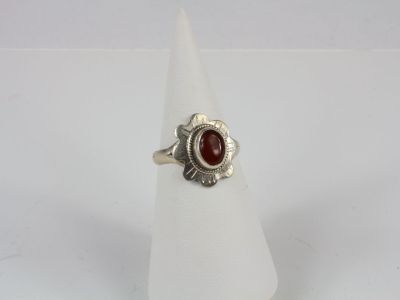 a close up of a silver ring with a red stone in it
