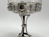 un plat ancien en argent surmonté d'un bol en verre