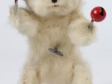 un ours en peluche blanc tenant deux balles rouges dans ses pattes