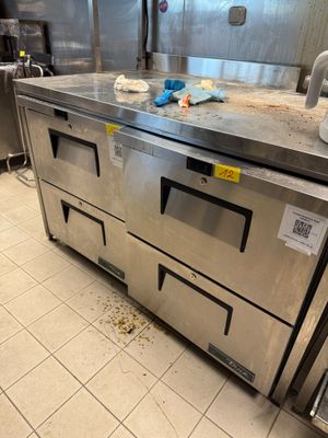 plan de travail en acier inoxydable dans une cuisine professionnelle où le sol est encombré
