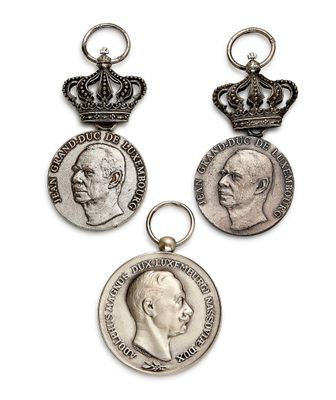 trois médailles d'argent ornées d'une couronne sur fond blanc