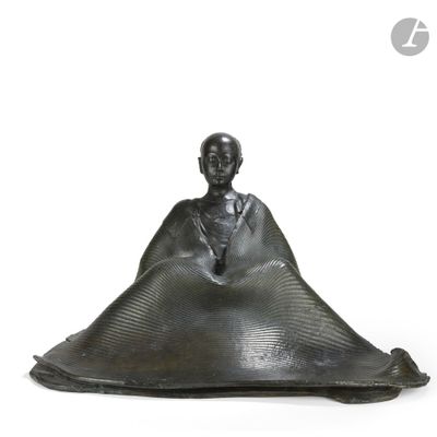 statue of a man sitting on a large piece of metal