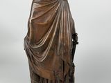 a bronze statue of a man with a cloak and a sword