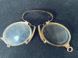 une paire de lunettes anciennes avec une monture en or et des verres bleus