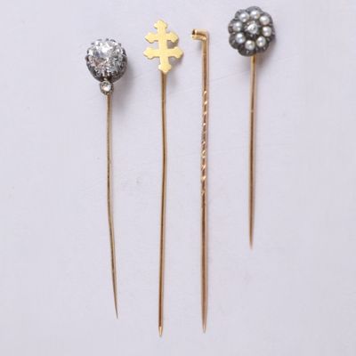 three gold and silver hair pins sitting on top of a white surface