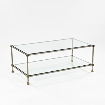 a glass coffee table with brass legs and a glass top