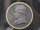 a bronze medallion of a man in a suit and tie