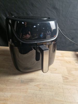 une friteuse à air chaud noire et argentée posée sur une table en bois