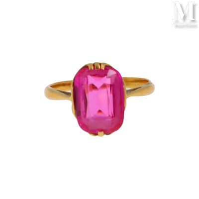 un gros plan d'une bague en pierre rose sur fond blanc