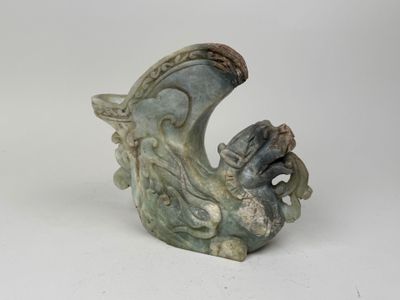 une petite statue de dragon posée sur une surface blanche