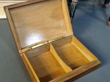 an open wooden box sitting on top of a floor next to a dresser