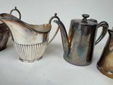 three silver pitchers and a silver pitcher on a table