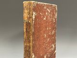 an old book sitting on top of a white table next to a gray wall