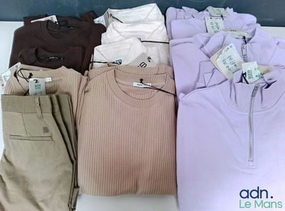 de nombreux t-shirts et pantalons de différentes couleurs posés sur une table
