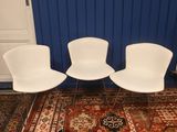 trois chaises blanches posées sur un tapis rouge dans une pièce