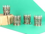 six silver shot glasses sitting on top of a table next to a wooden block