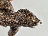 a hand that is holding a small statue of a turtle