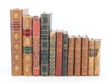 several old books are lined up in a row on a white surface