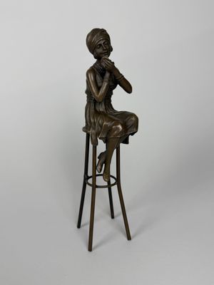 a bronze statue of a woman sitting on a stool with her hand on her chin